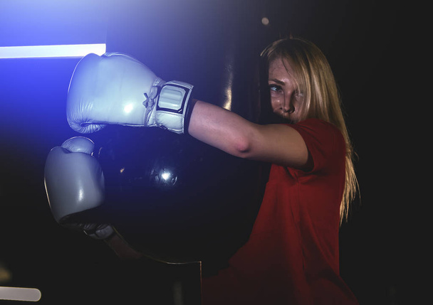 Young woman exercising in the gym. Woman hugging a punching bag - Fotografie, Obrázek