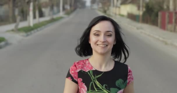 Atraktivní mladá žena v šatech s květinami pohybujícími se na kameře a úsměvů - Záběry, video