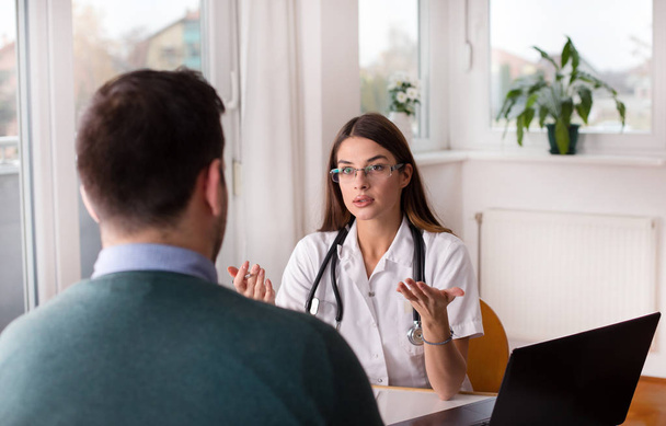 Arts en patiënt praten aan tafel - Foto, afbeelding