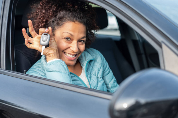 Zwarte vrouw nieuwe auto sleutels houden en glimlachend op camera - Foto, afbeelding