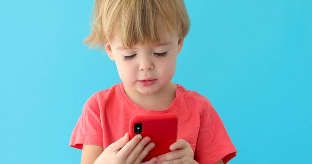 Child tapping cell phone screen, interest in modern technology - Foto, Imagen