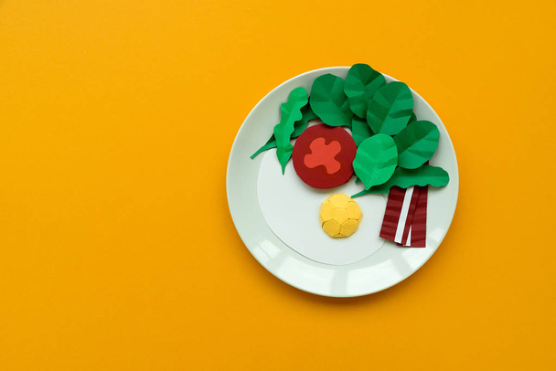 Continental breakfast made from paper: fried egg, tomato, bacon, spinach and arugula on yellow background. Minimal, creative, healthy or food art concept. Copy space. Top view - Foto, afbeelding