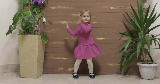 Kleine kind dans in de buurt bloempot en houten hek. Voel je gelukkig, glimlachend - Video
