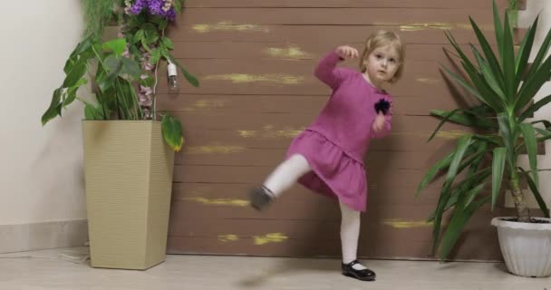 Malý dětský tanec poblíž květináčů a dřevěného plotu. Šťastný a usměvavý - Záběry, video