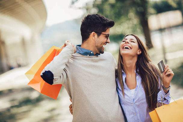 Portret van happy couple met boodschappentassen na het winkelen in CI - Foto, afbeelding
