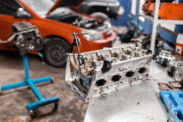 Selective focus. Engine Block on a repair stand with Piston and Connecting Rod of Automotive technology. Blurred car on background. Interior of a car repair shop. - Photo, Image