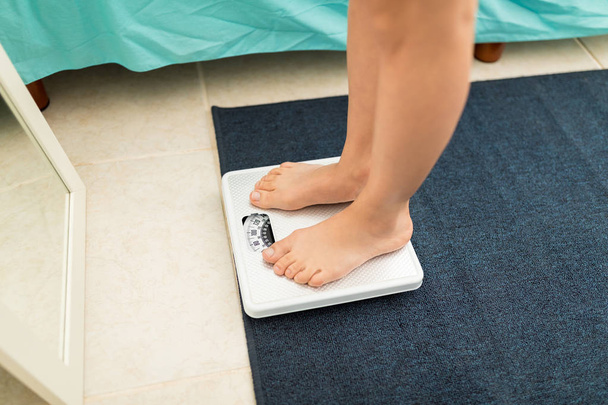 Low section of woman with bare feet standing on weight scale - Photo, Image
