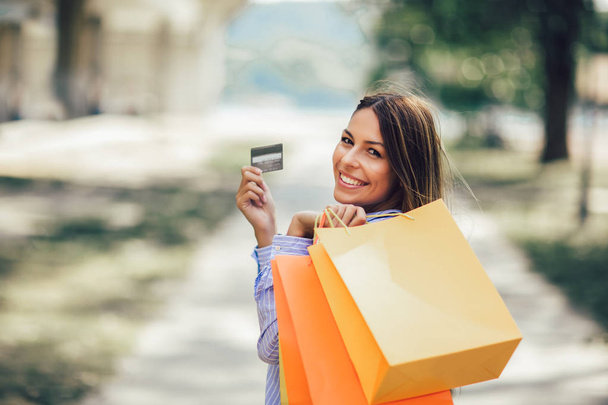 όμορφη κοπέλα κρατώντας τσάντες αγορών και μια πιστωτική κάρτα - Φωτογραφία, εικόνα