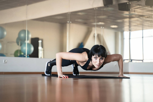 Young women at the gym doing push ups on a mat, fitness and healthy lifestyle concept - 写真・画像
