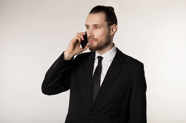 Selbstbewusster Mann in Formalwear mit trendigem Bart und Frisur, der ein Handy in der Hand hält - Foto, Bild