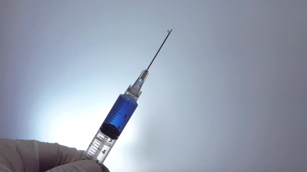 Ember Holding egy fecskendő csöpögő kék folyadék lassan - Felvétel, videó