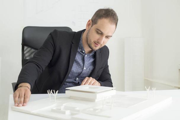 Businessman in the office is looking closely into the architecture of a modern house model - Фото, зображення