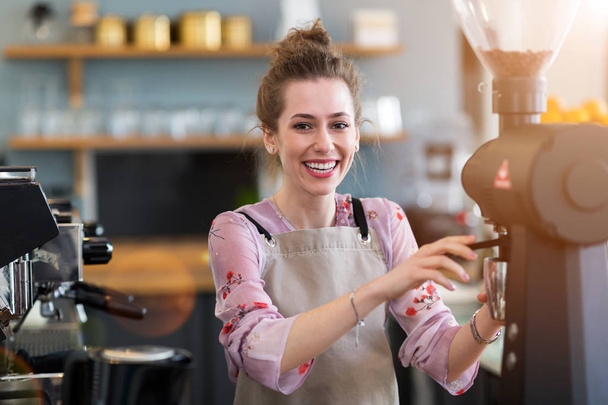Young barista preparing coffee for customers at her cafe counter - Zdjęcie, obraz