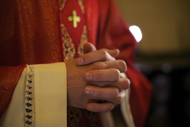 Katolinen pappi alttarilla rukoilee messussa
 - Valokuva, kuva
