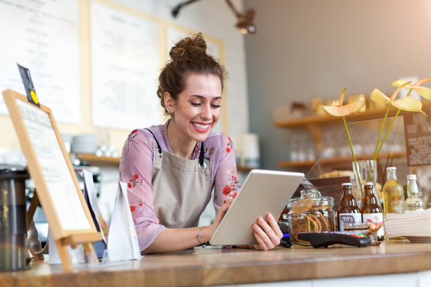 Jonge vrouw met behulp van digitale tablet in coffeeshop - Foto, afbeelding