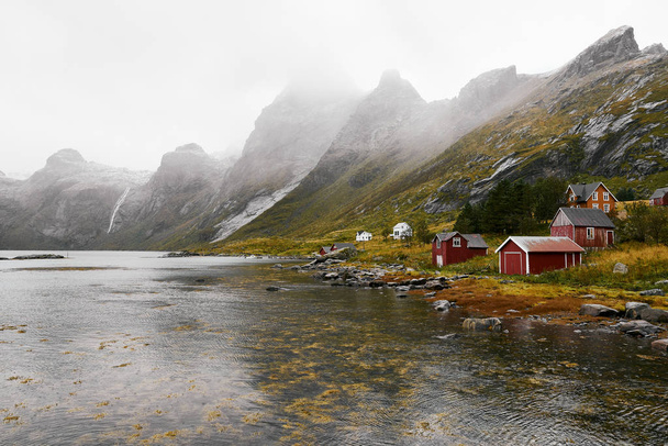 Vista panorámica de un remoto pueblo de pescadores en la costa de Vinstad con montañas al fondo en las islas Lofoten en Noruega
. - Foto, Imagen