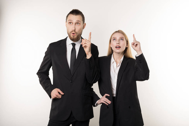Dois parceiros de negócios atraentes em ternos pretos tiveram uma ideia de como melhorar seus negócios
 - Foto, Imagem