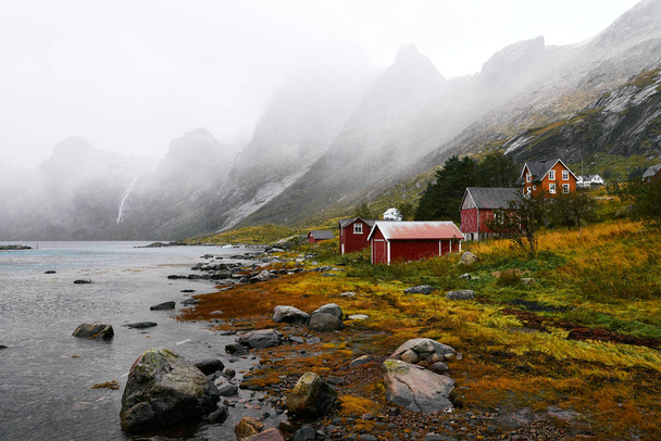 ノルウェーのロフォーテン諸島を背景に山々が立つヴィンスタッドの海岸にある遠く離れた古い漁村のパノラマビュー. - 写真・画像