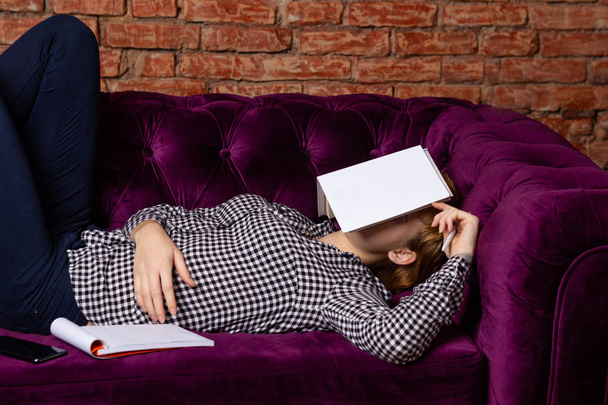 Female student exhausted and sleeping on sofa. - Foto, afbeelding
