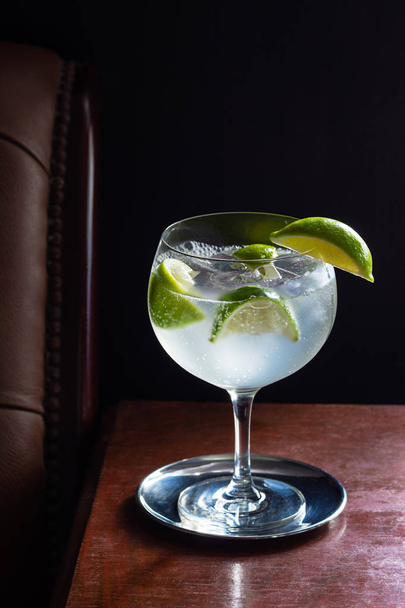 Cold Gin and Tonic or Vodka Tonic Cocktail in a Goblet with Ice and Limes in a Dark Luxurious Bar - Φωτογραφία, εικόνα