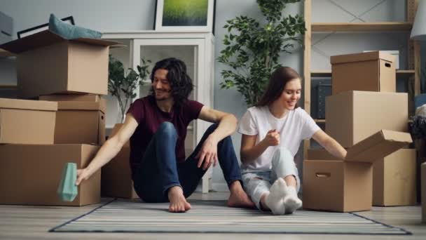Молода жінка бере речі з коробки і розмовляє з хлопцем під час переїзду
 - Кадри, відео