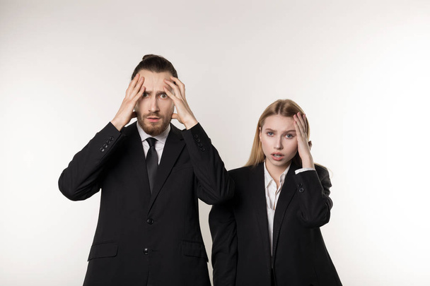 Due giovani dipendenti in completo nero in piedi con le mani sulla testa, licenziati dopo il fallimento della loro azienda
 - Foto, immagini