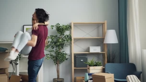 Loving boyfriend entering new flat with girl in his arms kissing and whirling - Materiaali, video