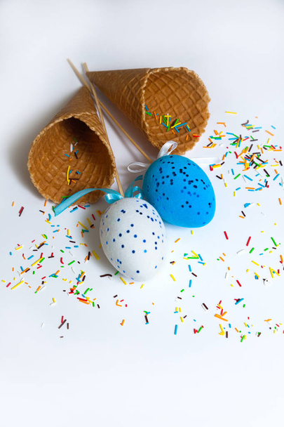 easter two eggs blue white multicolored background yellow bow ribbon italian cono waffle cup candy - Foto, Imagem