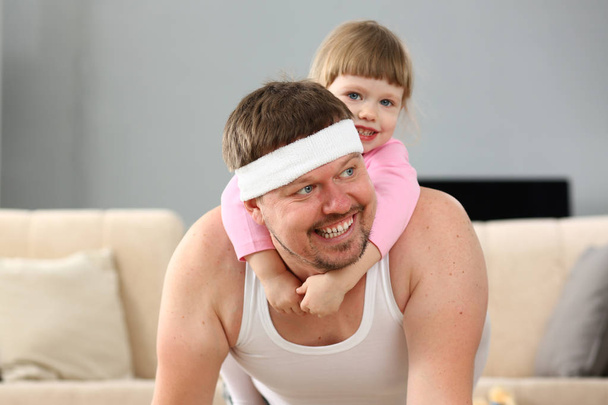 Cute little girl riding her father at home playing - Photo, Image