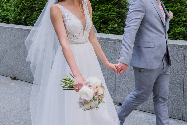 The bride and groom are standing together near the office building. - Foto, Imagem