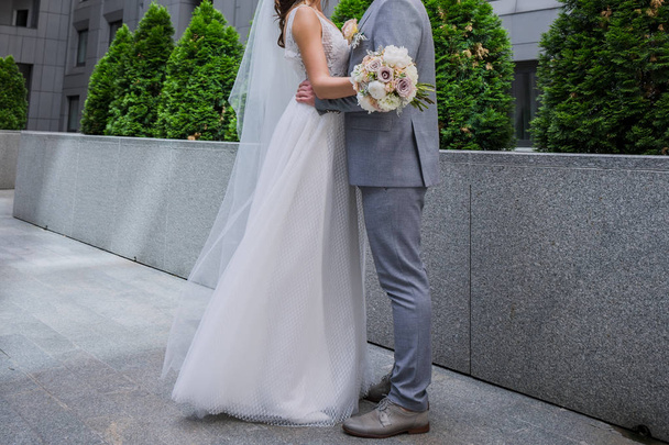 The bride and groom are standing together near the office building. - Fotó, kép
