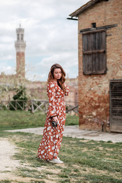A beautiful girl in a long dress walking around the ancient  city of Siena  - Fotó, kép