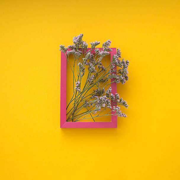 small pink flowers on a yellow background in a frame - Фото, изображение