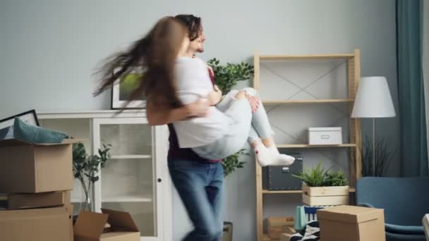 Happy couple whirling and kissing in new apartment then talking looking around - Imágenes, Vídeo