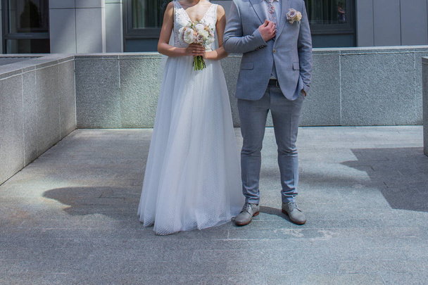 The bride and groom are standing together near the office building. - Φωτογραφία, εικόνα