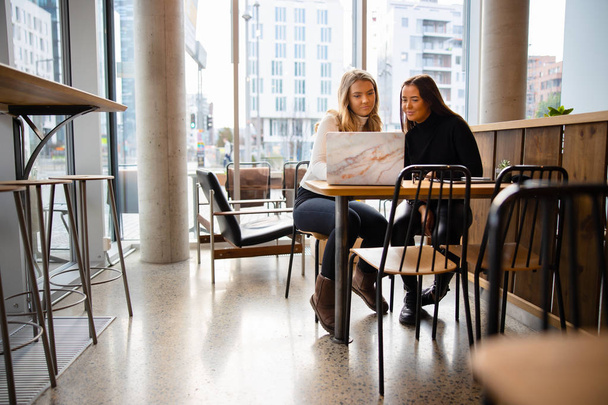 Estudiantes que trabajan en un proyecto de tarea común en una cafetería moderna
 - Foto, imagen