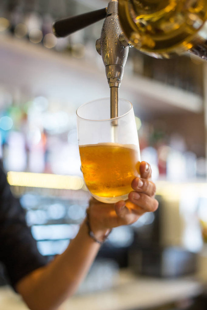 Barmann Hand am Zapfhahn schenkt Lagerbier aus, das in einem Restaurant oder Pub ausgeschenkt wird - Foto, Bild