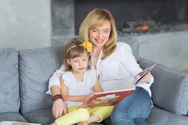 Mother and little daughter are playing, reading a book, sitting  - Фото, зображення