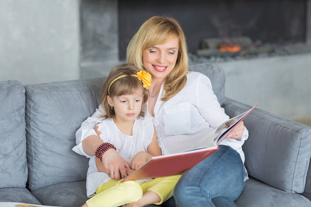 Mother and little daughter are playing, reading a book, sitting  - Foto, Imagem