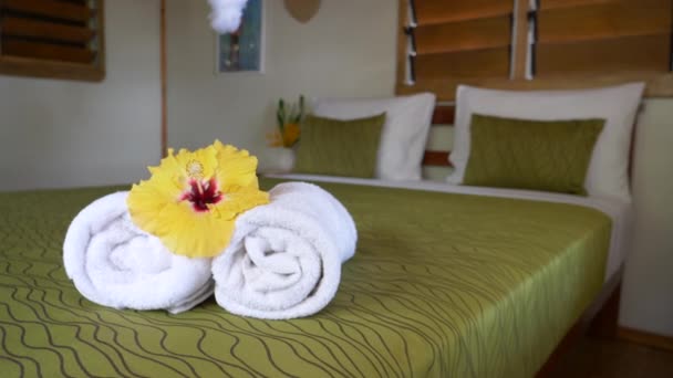 Close Up Sarı ebegümeci çiçeği düzgün bir şekilde dekore edilmiş bir otel yatak odasında havlu yuvarlandı üstüne çırpınan. Tropik bir tesiste hoş karşılanıyor romantik bungalov. Tatilde gevşemek için sakin saklanma yeri - Video, Çekim