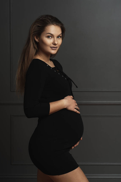 Retrato hermosa joven embarazada tocando suavemente con las manos su vientre, ella está esperando una nueva vida
 - Foto, imagen
