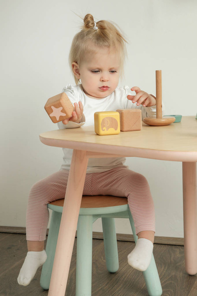 Adorable baby girl spending time in the nursery room, playing with wooden blocks - Foto, Imagen