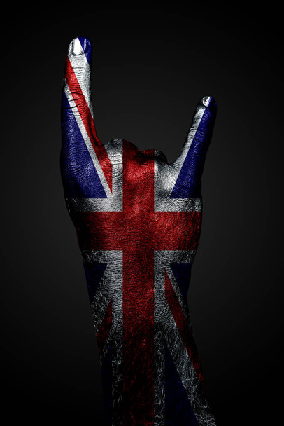 Une main avec un drapeau dessiné du Royaume-Uni montre un signe de chèvre sur un fond sombre
 - Photo, image