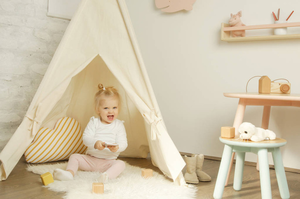 Close up retrato de uma menina sob uma tenda tipi em seu quarto de berçário
 - Foto, Imagem