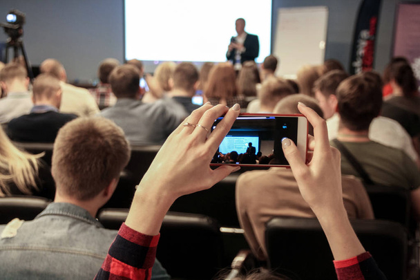 Mujer toma una foto durante la conferencia con un smartphone
 - Foto, imagen