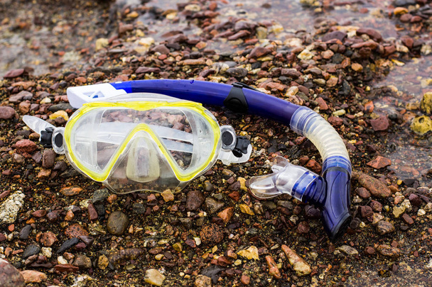 summer season sport and activity concept picture with cheap snorkeling equipment mask and tube on stone coast line ground - Photo, Image