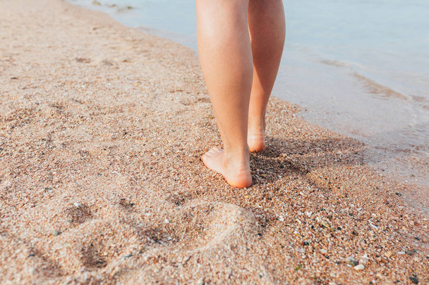 Mujer caminando en la playa dejando huellas en la arena
  - Foto, Imagen