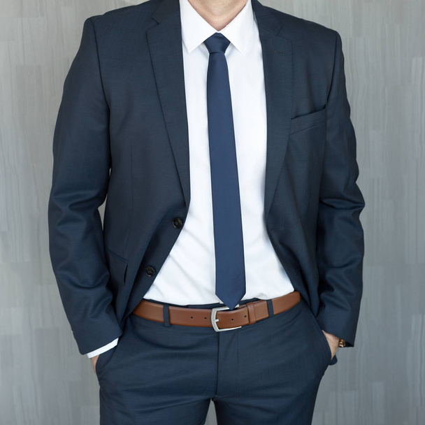 Oberkörper eines Geschäftsmannes, der mit in der Mitte geballten Händen in einem klassischen marineblauen Anzug steht. - Foto, Bild