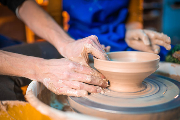 Traditional pottery making, man teacher shows the basics of pottery in art studio. Artist operates hands, which gently creating correctly shaped jug handmade from clay - Foto, Bild