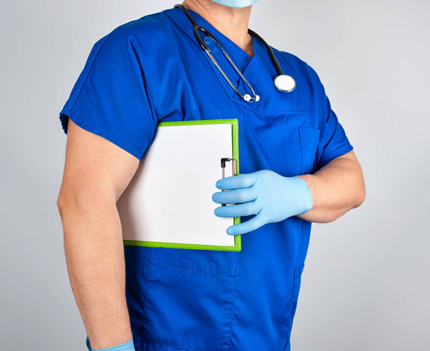 doctor in blue uniform and sterile latex gloves holds clipboard - Fotografie, Obrázek
